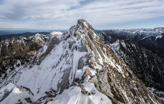 Three mountaineers on a rocky snowy ridge, hiking trail to Ammergauer Hochplatte, view of mountain panorama, behind summit Ammergauer Hochplatte, in autumn, Ammergauer Alps, Bavaria, Germany