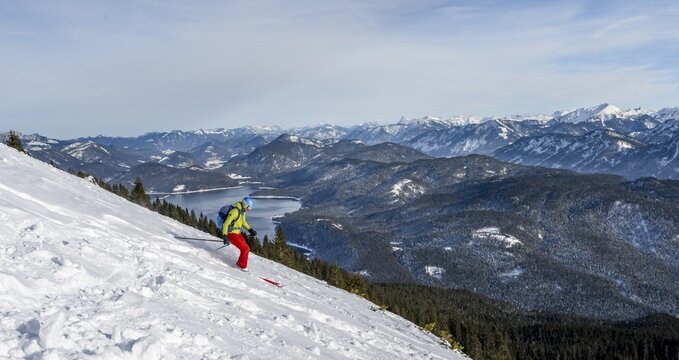 Skiers skiing down the Simetsberg, view of Walchensee and mountain panorama, Estergebirge, Bavarian Prealps, Bavaria Germany