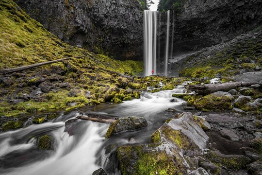 Young woman standing in front of waterfall, Tamanawas Falls, long exposure, Cold Spring Creek wild river, Oregon, USA