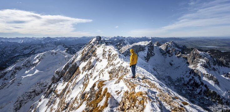 Climbers on a narrow rocky snowy ridge, behind peak crow, view of mountain panorama, hiking to Ammergauer Hochplatte, in autumn, Ammergau Alps, Bavaria, Germany