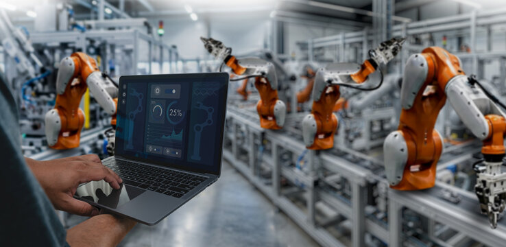Smart industry control concept with hands holding a tablet for monitoring automated robotic machines in a modern manufacturing facility, representing industrial automation, digital production control.