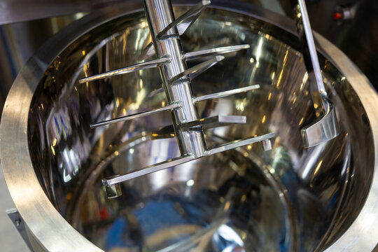 Stainless steel industrial mixing tank with a mechanical agitator shaft.