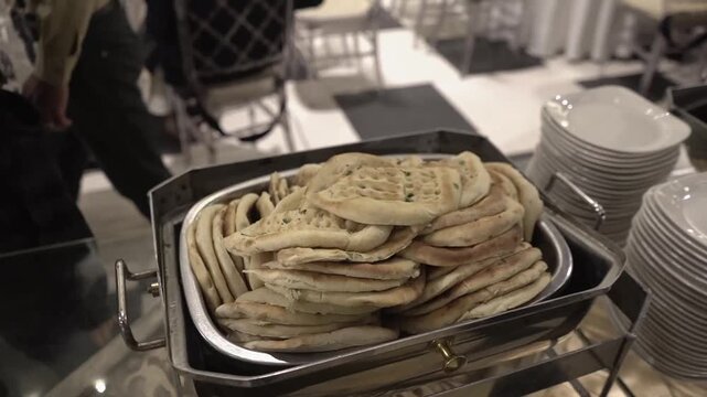 Close-up footage of a traditional Naan (roti) dish served at a wedding buffet. Professional catering setup featuring freshly prepared rice for guests at a reception, banquet, or celebration event. Ide
