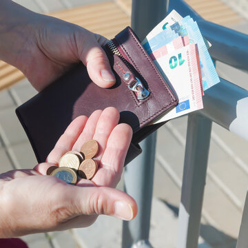 Leather purse, euro banknotes and coins in female hands, selective focus.