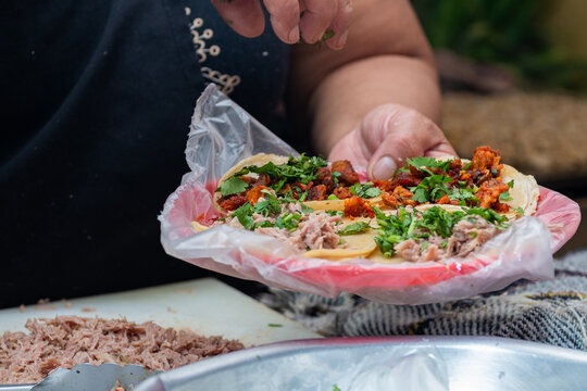 Close-up of hands preparing fresh street tacos with meat, onion and cilantro