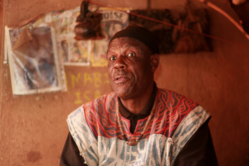 Obraz premium A traditional healer, spiritual leader, and custodian of indigenous knowledge, dressed in ceremonial attire, welcomes visitors in his home in the Babungo Kingdom, Cameroon. 