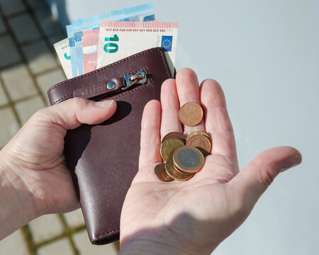 Leather purse,  euro banknotes and coins in female hands, selective focus.	