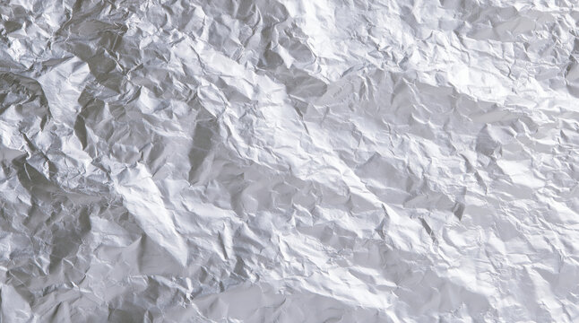Crumpled aluminum foil texture, silver metal surface with wrinkles and folds, abstract background with reflective pattern