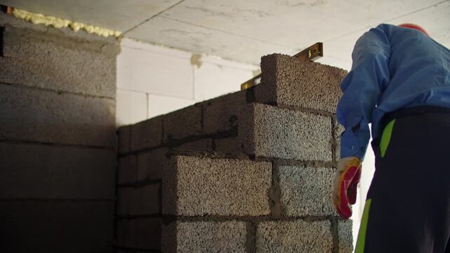 Construction worker laying concrete blocks on building site