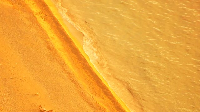 Beach waves sunset golden light reflecting on calm ocean water washing against a peaceful sandy shoreline at dusk