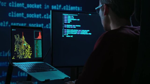 Focused coder works at desk in a dark office with programming code lines running behind. Developer is deeply engaged in a late night data science or AI coding session. 