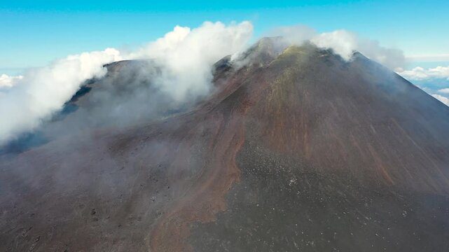 A drone view of Smoke drifts from Mount Teide's volcanic slopes, set against blue sky in Tenerife, Spain