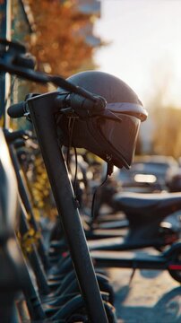 Black helmet resting on electric scooter handlebars in a row of parked scooters under warm sunlight, showcasing urban mobility and safety gear in a city setting