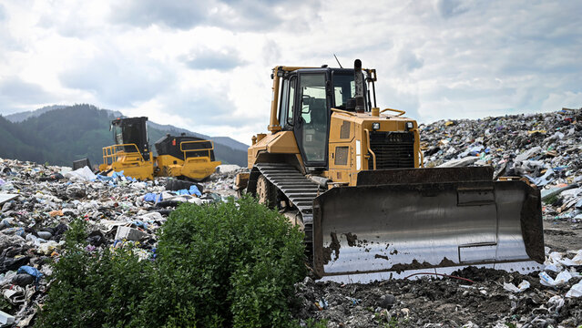 Heavy industrial machinery working at a large landfill site.