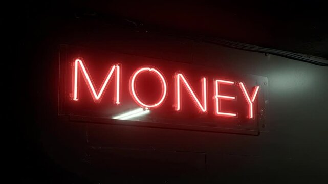 Red neon sign spelling the word MONEY glows brightly in the dark