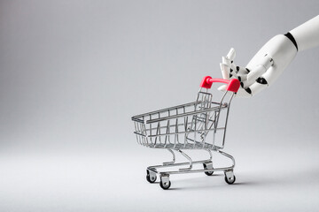 A robotic white hand holding a miniature shopping cart on a white background. Concept of artificial intelligence, automation and future of retail and e-commerce © PixelArt_25