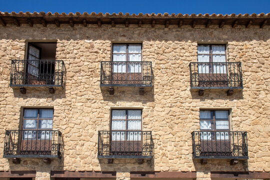 Traditional manor house facade in Medinaceli, Soria, Spain, featuring wooden doors, wrought-iron balconies, and elegant white curtains, reflecting the charm of historic Castilian architecture.