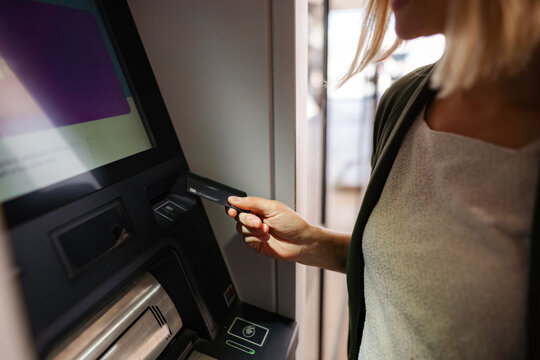 Woman inserting credit card into ATM for banking transaction