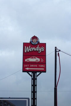 Tbilisi, Georgia - December 04, 2025: Vertical photo. Stele with restaurant sign with logo of fast food cafe Wendy's, redhead girl face, car icon, text Drive thru. Concept of lunch, pick up order, eat