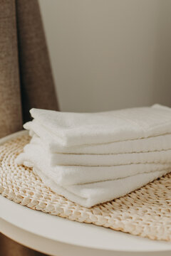 Minimalist still life of luxury spa essentials. White cotton towels with visible textured on a table.
