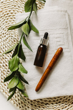 Minimalist still life of luxury spa essentials. A glass bottle with a serum on a white towel surface. The overall feeling is pure and luxurious.
