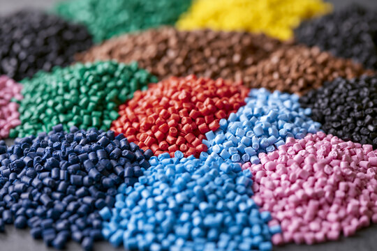 High-angle view of various heaps of colorful industrial plastic granules and polymer pellets including PE, ASA, PP, and PA resins for injection molding and manufacturing material production.