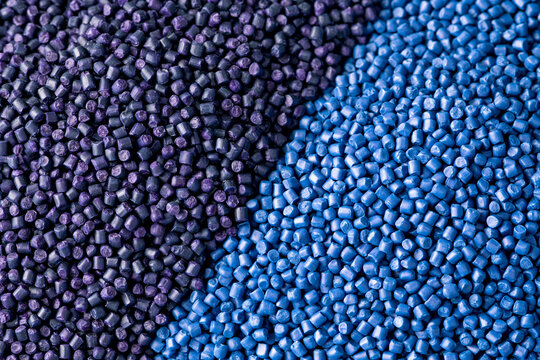 Macro photograph showcasing a detailed heap of industrial plastic granules in vibrant blue and deep purple hues, representing raw polymer materials like PE, ASA, PP, and PA for manufacturing.