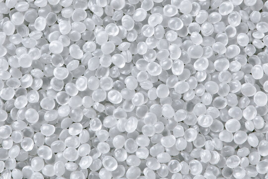 High-resolution macro shot of white translucent plastic granules and polymer pellets used as raw materials in industrial manufacturing for PP, PE, PA, and ASA products in a dense pile.
