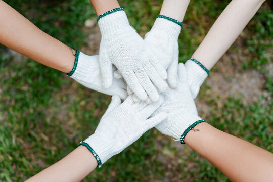 Group of diverse hands wearing work gloves stacking together in a united gesture, symbolizing teamwork, collaboration, and community spirit for a joint project outdoors