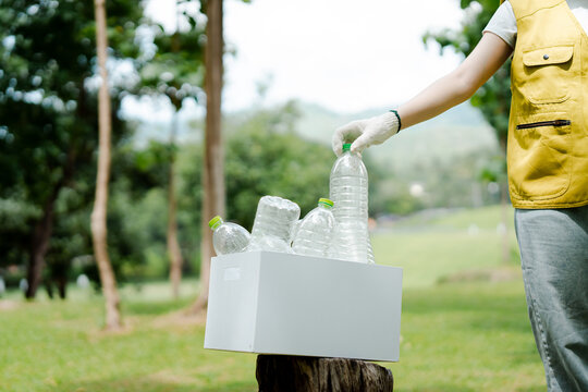 Person taking plastic bottles from a box for recycling, contributing to environmental protection and waste management, focusing on sustainability