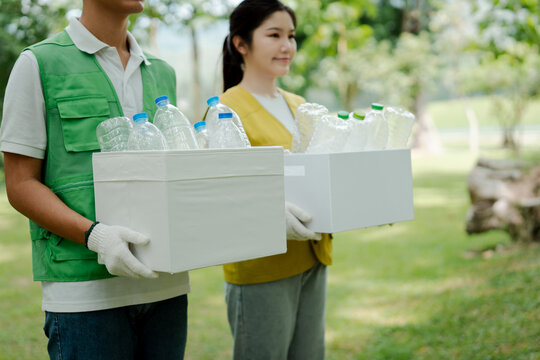 Volunteers collecting recyclable plastic bottles in boxes, contributing to environmental protection, waste management, and sustainable living initiatives outdoors
