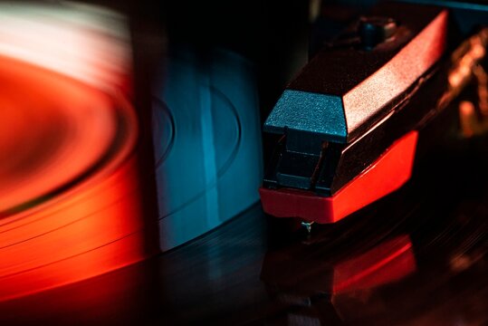 Record player needle reading vinyl record grooves with red light