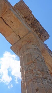 Young female tourist waving from ancient ruins of Zeus temple in Nemea, Greece