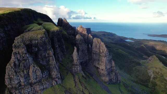 Dramatic, aerial, parallax shot of the Needle, a rocky pinnacle at the Quiraing on the Isle of Skye, Scotland with a view of the sea on a clear day
