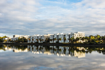 Fototapeta premium Reflections of white waterfront apartments and surrounding greenery along the Parramatta River, mirrored cleanly in the still water.