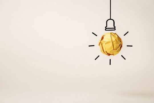 Crumpled yellow paper ball hanging as a lightbulb idea
