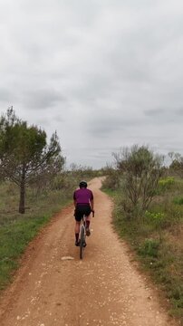 Drone low angle tracking shot following a gravel cyclist in a purple jersey