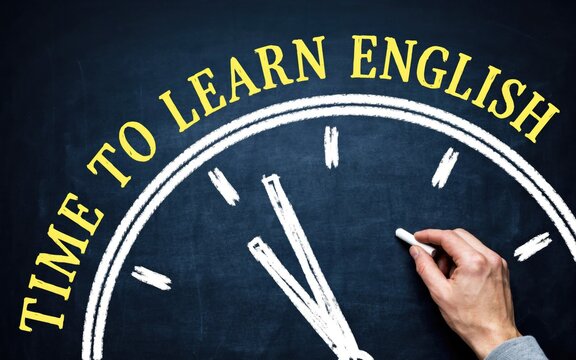 Time to learn english text written in yellow chalk on a blackboard clock