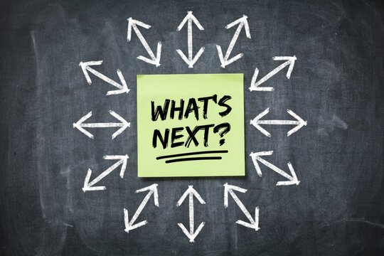 What's next text on a bright green sticky note with chalk arrows on blackboard