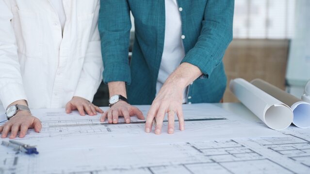 Architects collaborating on project blueprints, discussing building plans and engineering designs in an office setting. Architecture and business concept