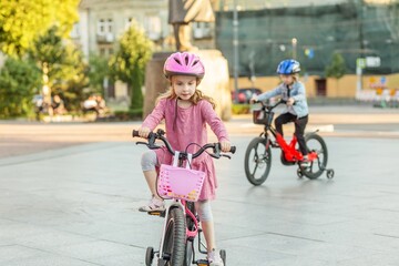 Fototapeta premium Children riding bicycles together wearing safety helmets