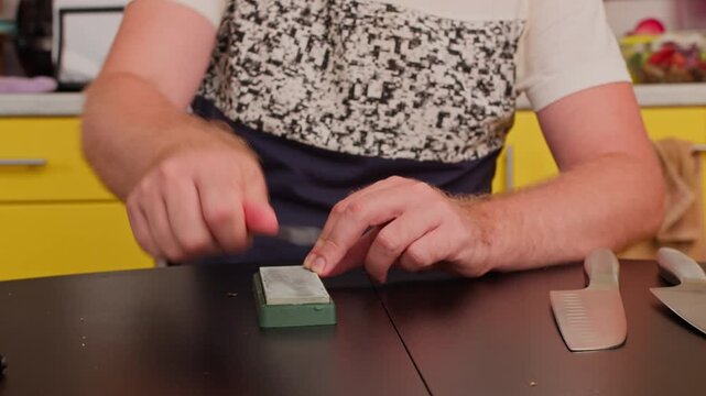 Man hands are shown sharpening kitchen knife on green stone. Useful for culinary blogs, cooking tutorials, kitchenware brands