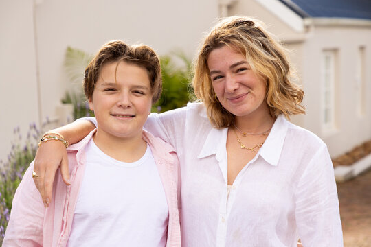 pre teen and young woman siblings smiling and embracing