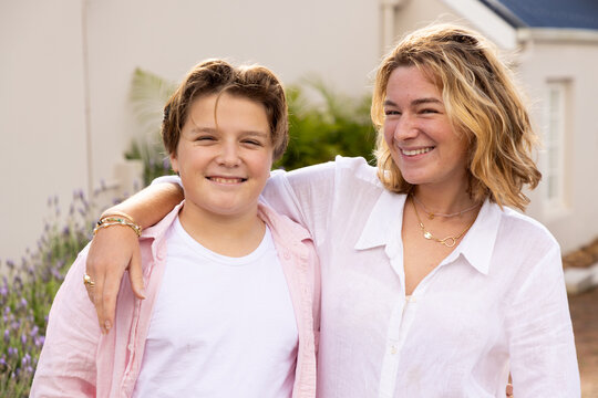pre teen and young woman siblings smiling and embracing