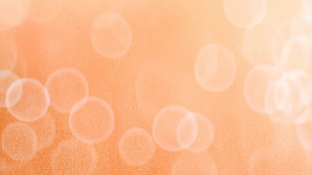 Abstract bokeh light patterns transition seamlessly through a soft orange gradient background