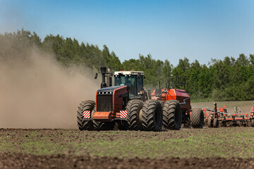 Fototapeta premium Powerful tractor with air seeder working on agricultural field during spring sowing