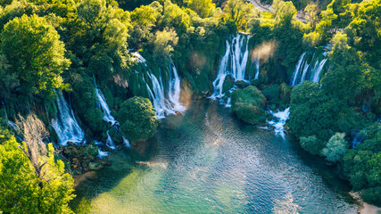Bird's-eye view of cascading waterfalls surrounded by dense vegetation, showcasing the vibrant colors and natural charm of Kravica Falls © Sanja
