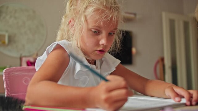 Schoolgirl working on assignment at home desk with mother supervising. Homework and studying concept