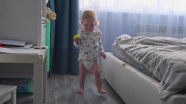 Little girl learning to walk indoors during early stage of independent movement. First steps at home