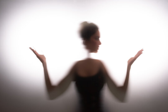 Woman stretching hands behind frost glass. Doubts and decision making concept